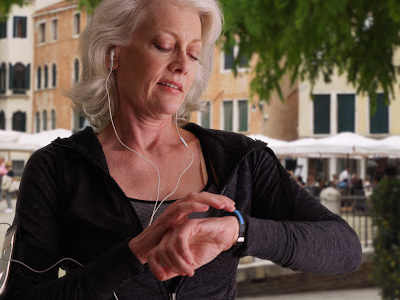 Older woman with white hair looking at smartwatch when out for a walk